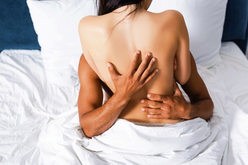A couple getting under the covers and fucking each other crazy as she rides him on top as he runs his fingers up her back.